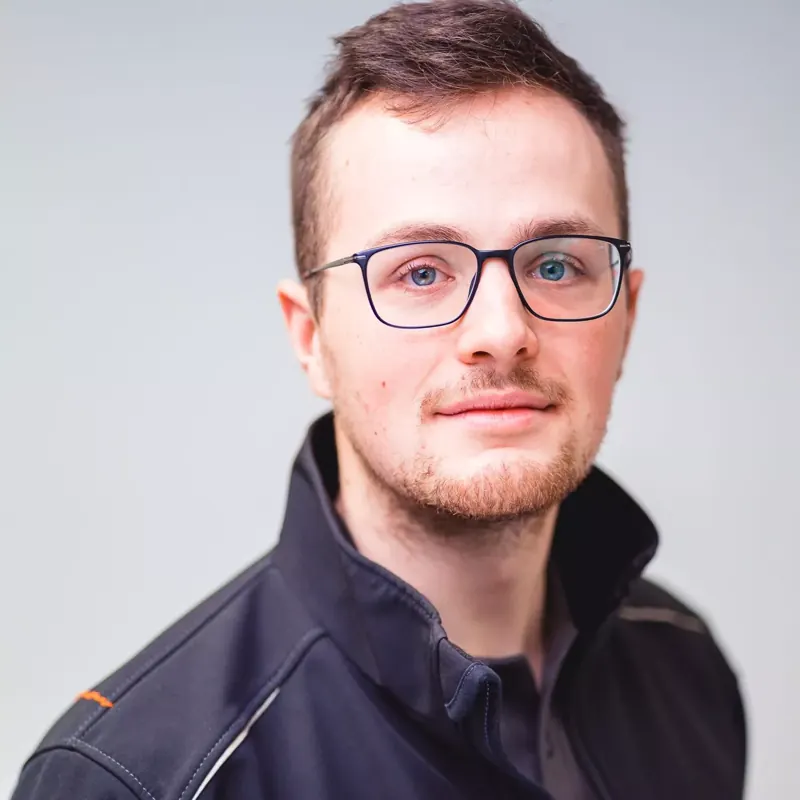 Porträt eines jungen Mannes mit Brille vor hellem Hintergrund